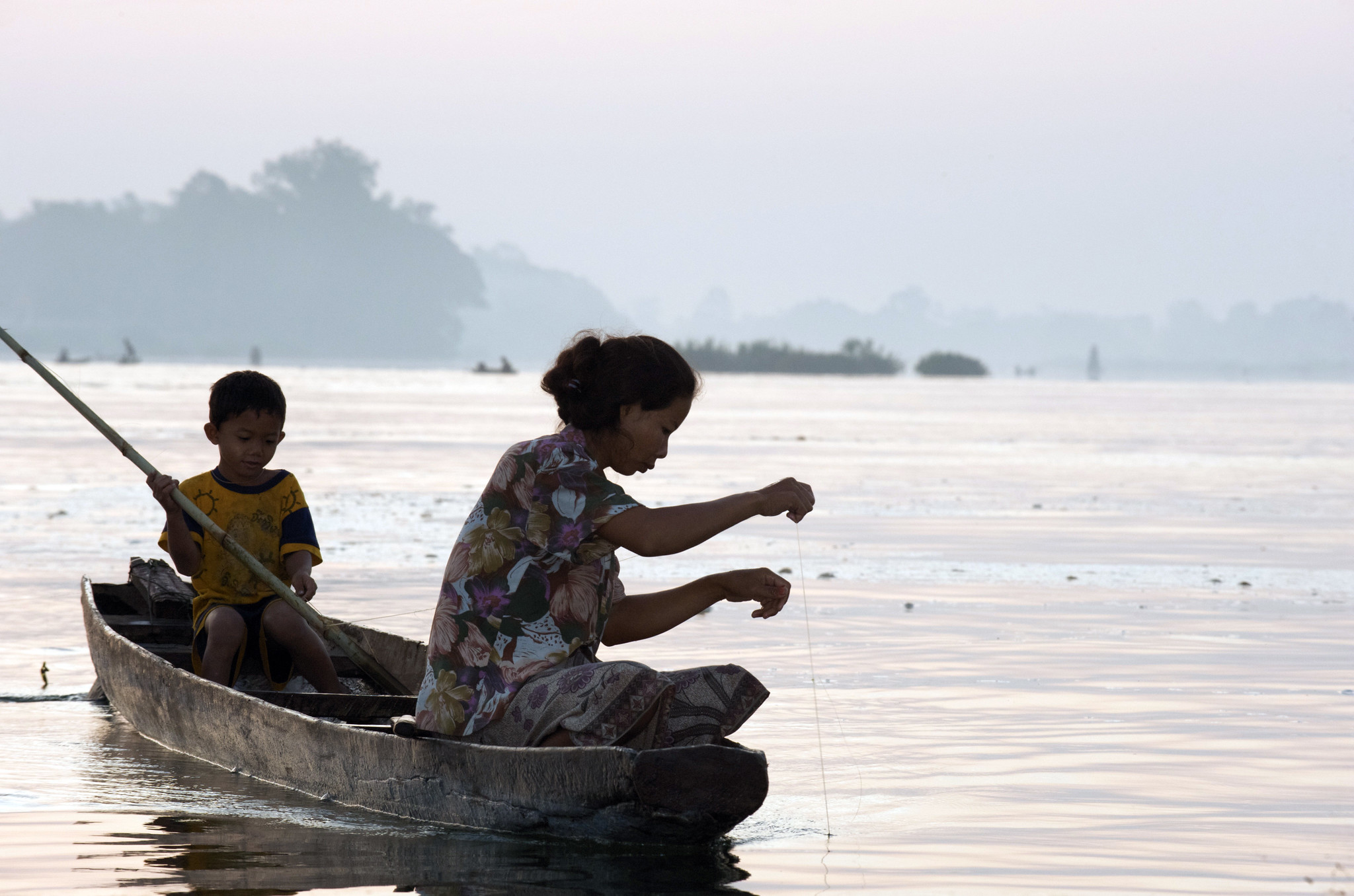 A fisherwoman checks her fishing line in the Mekong River in Laos. Photo by Patrick Dugan.