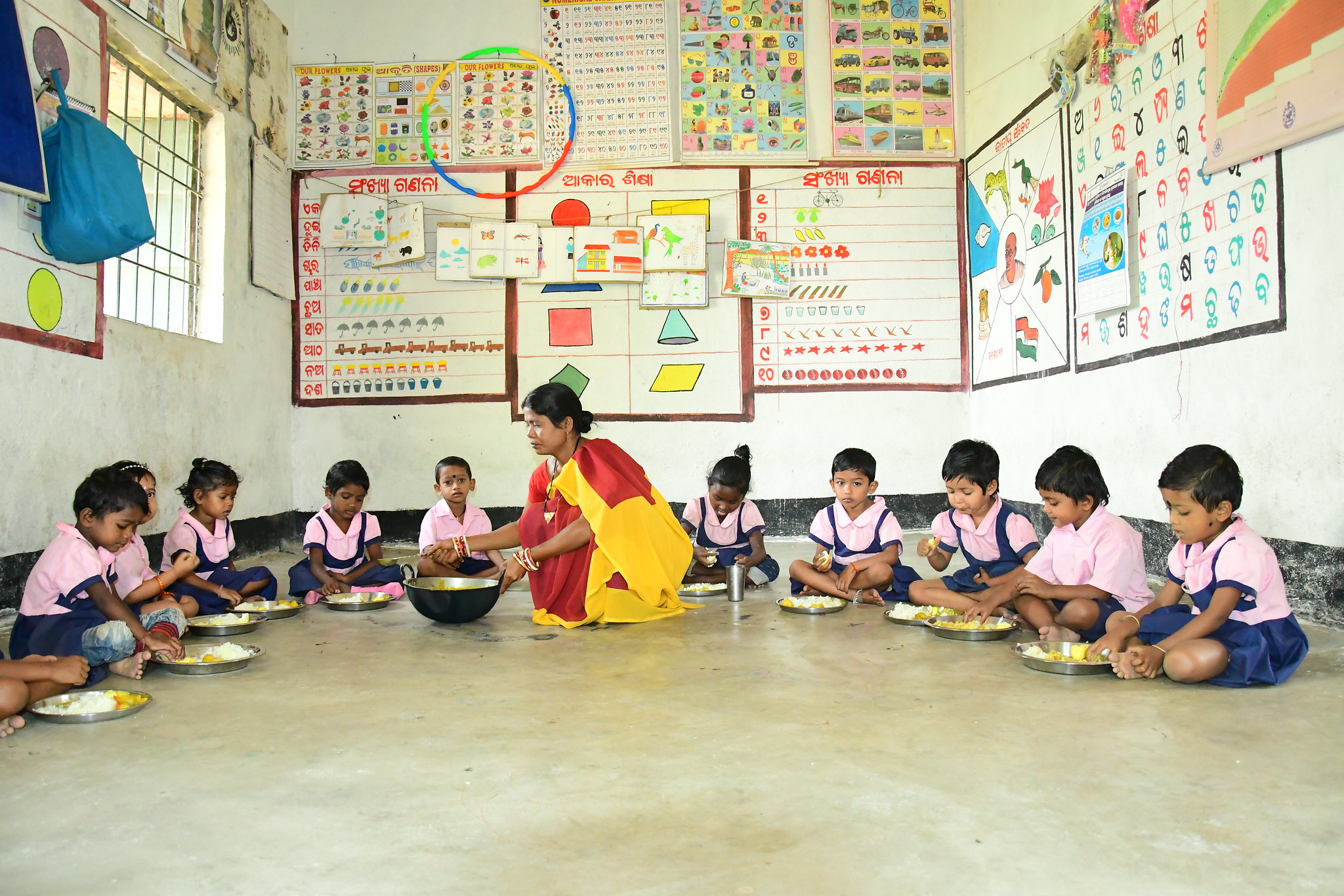 Children at the Bangabandha Anganwadi center (childcare center) enjoying small fish in hot cooked meals as part of the of Supplementary Nutrition Programme