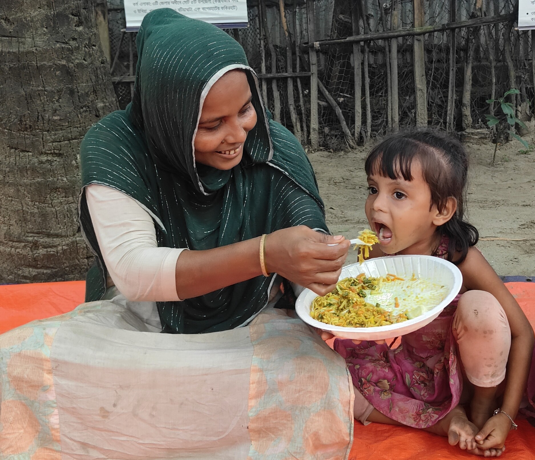 A woman feeds her child during a cooking demonstration using seaweed and green mussels in Cox’s Bazar, Bangladesh. These nutrient-rich foods provide protein, iron and essential micronutrients that support child growth and development.