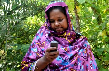 A Bangladeshi fisherwoman receives payment on her mobile phone. Photo by Sayma Islam.