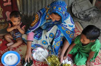 A Bangladeshi mother feeding her children nutrient-rich small fish and leafy vegetables. Photo by Finn Thilsted. 