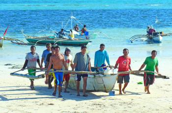 Fishers practice the Filipino value of bayanihan, helping each other with arduous tasks, as they haul their boats after the morning catch. Photo by Idohna Leah Buendia.