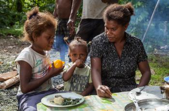 A mother and her daughters share a meal of Mozambique tilapia, cabbage and potato with coconut milk, Taflankwasa village, Malaita Province, Solomon Islands. Photo by Filip Milovac.