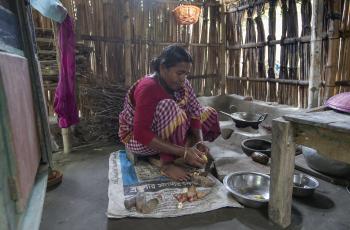 A woman cooking mola and potato curry in her kitchen in Khulna, Bangladesh. Photo by Yousuf Tushar.