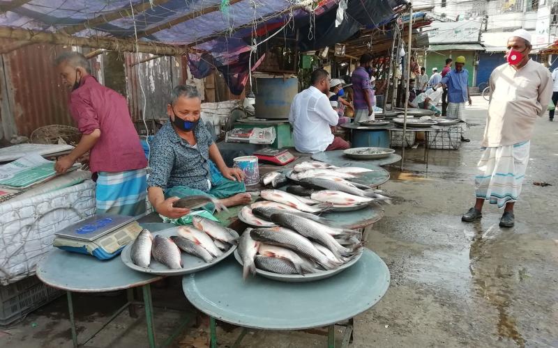Masked retailers sell fish at a market in Chandpur, Bangladesh. Photo by Kingkar Shaha.