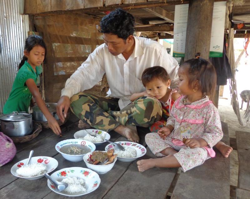 A family shares a meal with fish, Cambodia. Photo by Sean Vichet.