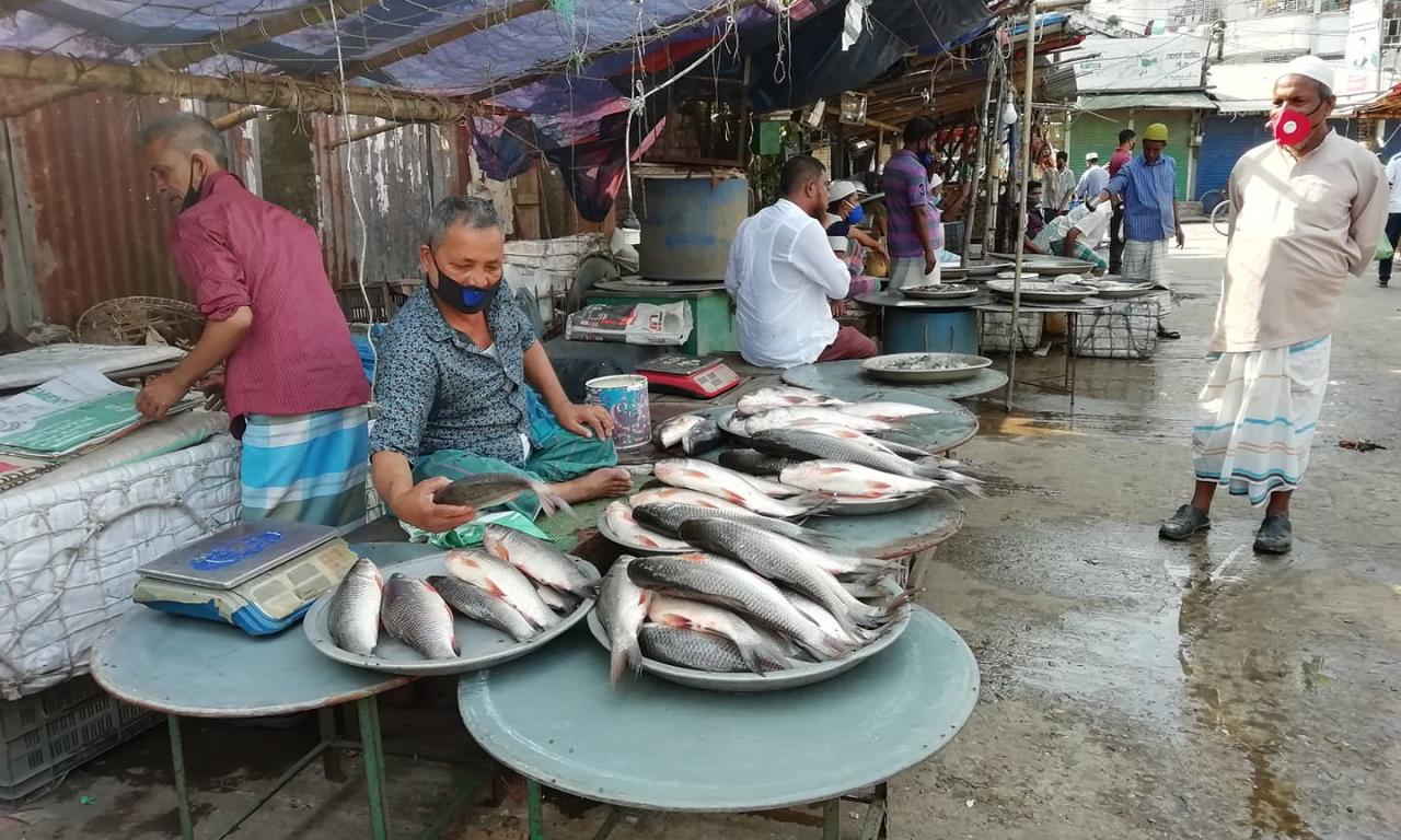 Masked retailers sell fish at a market in Chandpur, Bangladesh. Photo by Kingkar Shaha.