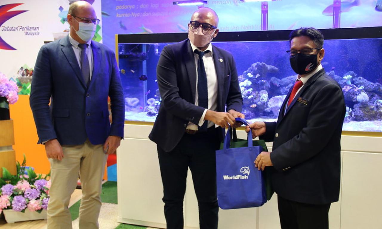 WorldFish Interim Director General Essam Yassin Mohammed hands the Acting Director General of the Department of Fisheries a bag of WorldFish souvenirs while WorldFish Interim Director for Science and Research Eddie Allison looks ons. Photo by Sean Lee Kuan Shern